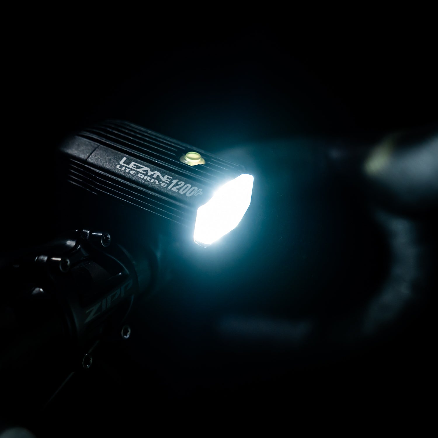 Lezyne Lite Drive 1200+ LED front bike light with up to 60-hour runtime, mounted on a gravel bike handlebar for night rides.
