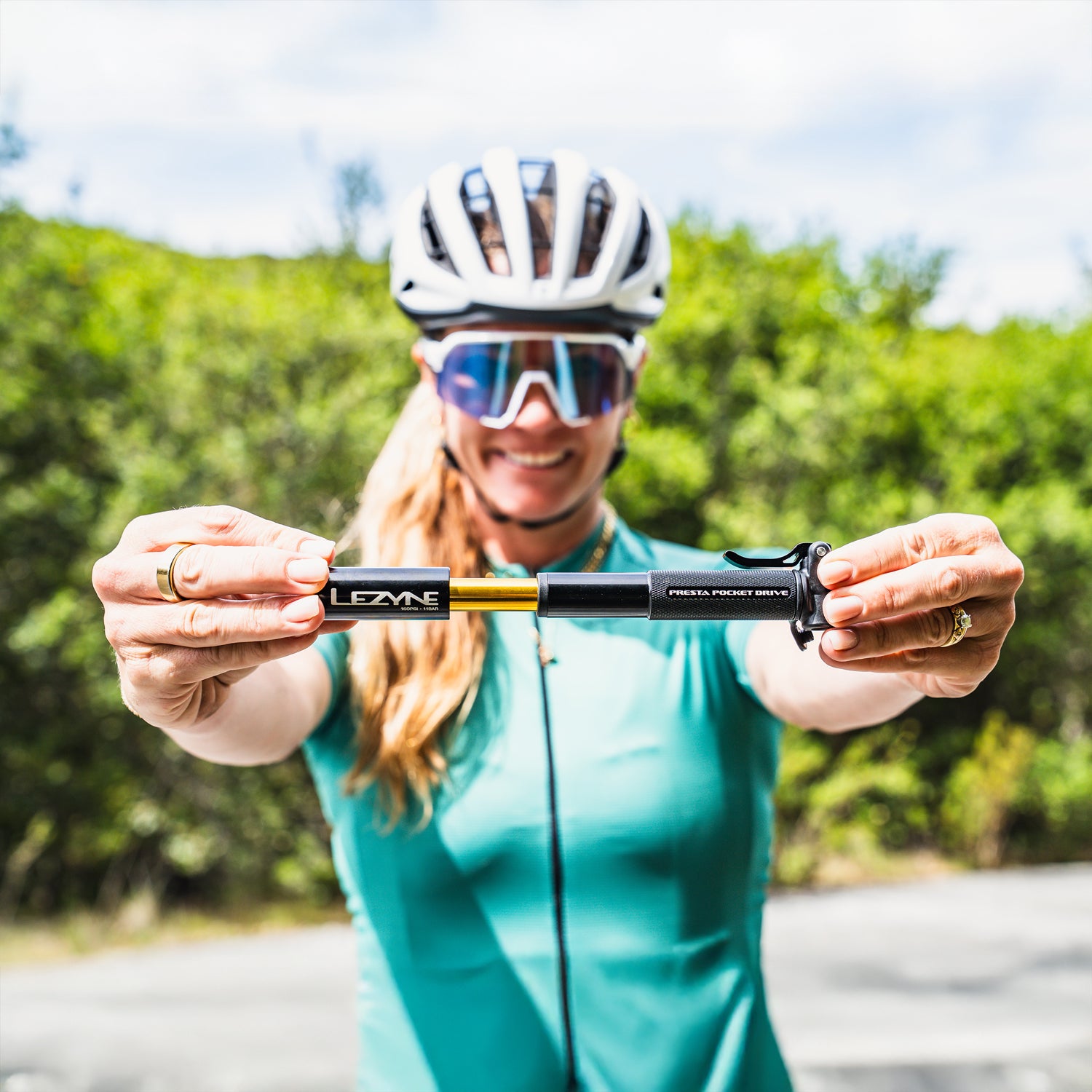 Road cyclist holding the Presta Pocket Drive bike hand pump, showing off its compact size and clean design mid-ride.