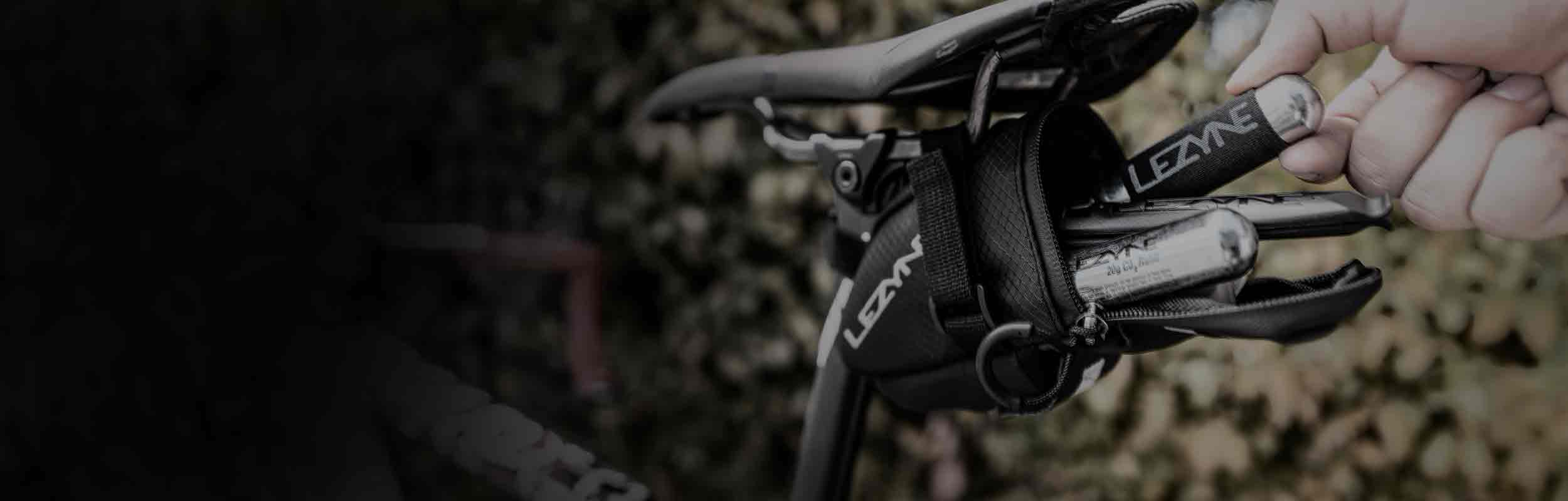 Tools and CO2 canisters being removed from a bag that is mounted under a bicycle seat.
