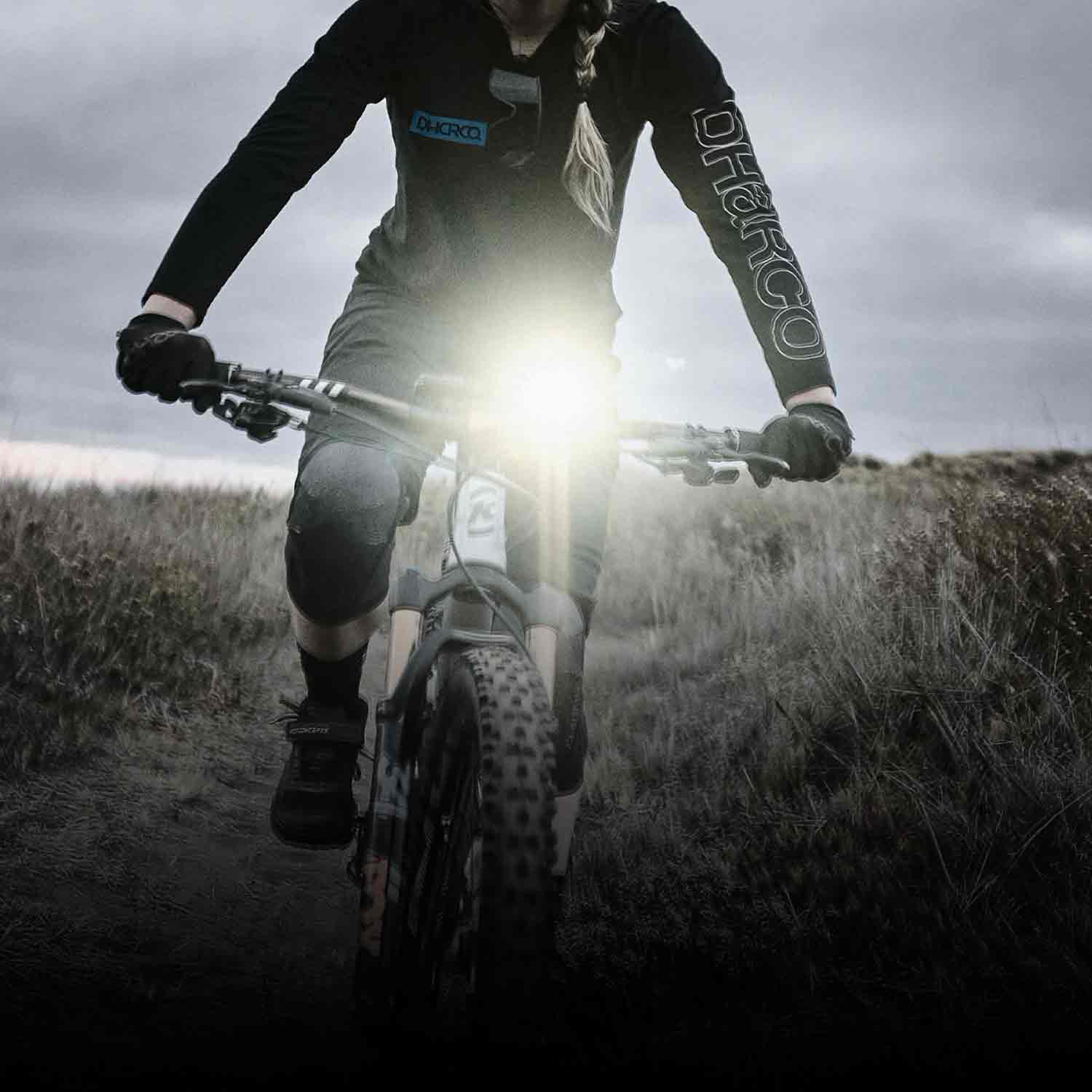 A very bright front bicycle light on a bicycle that is being ridden on rough terrain.