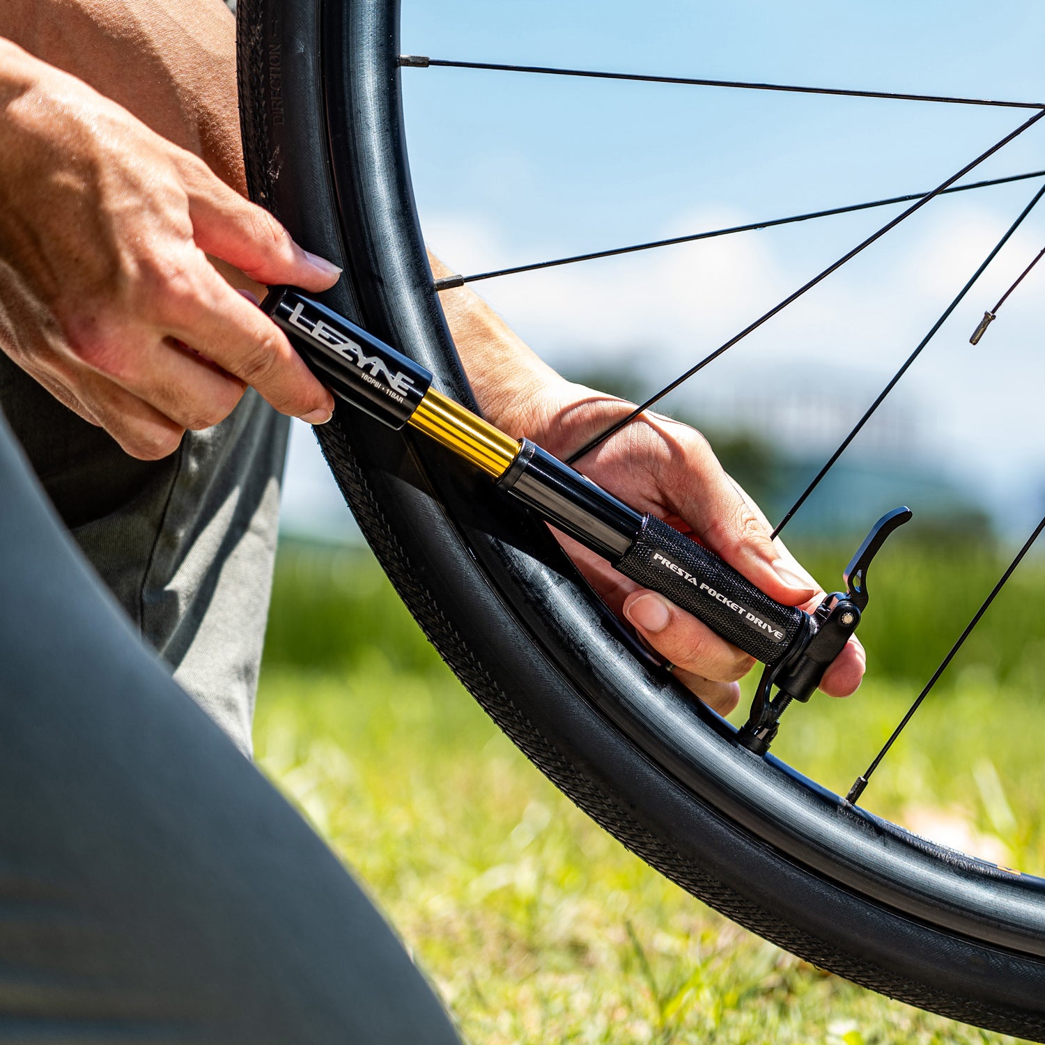Road cyclist inflating tire with the Presta Pocket Drive bike hand pump, demonstrating control and compatibility.