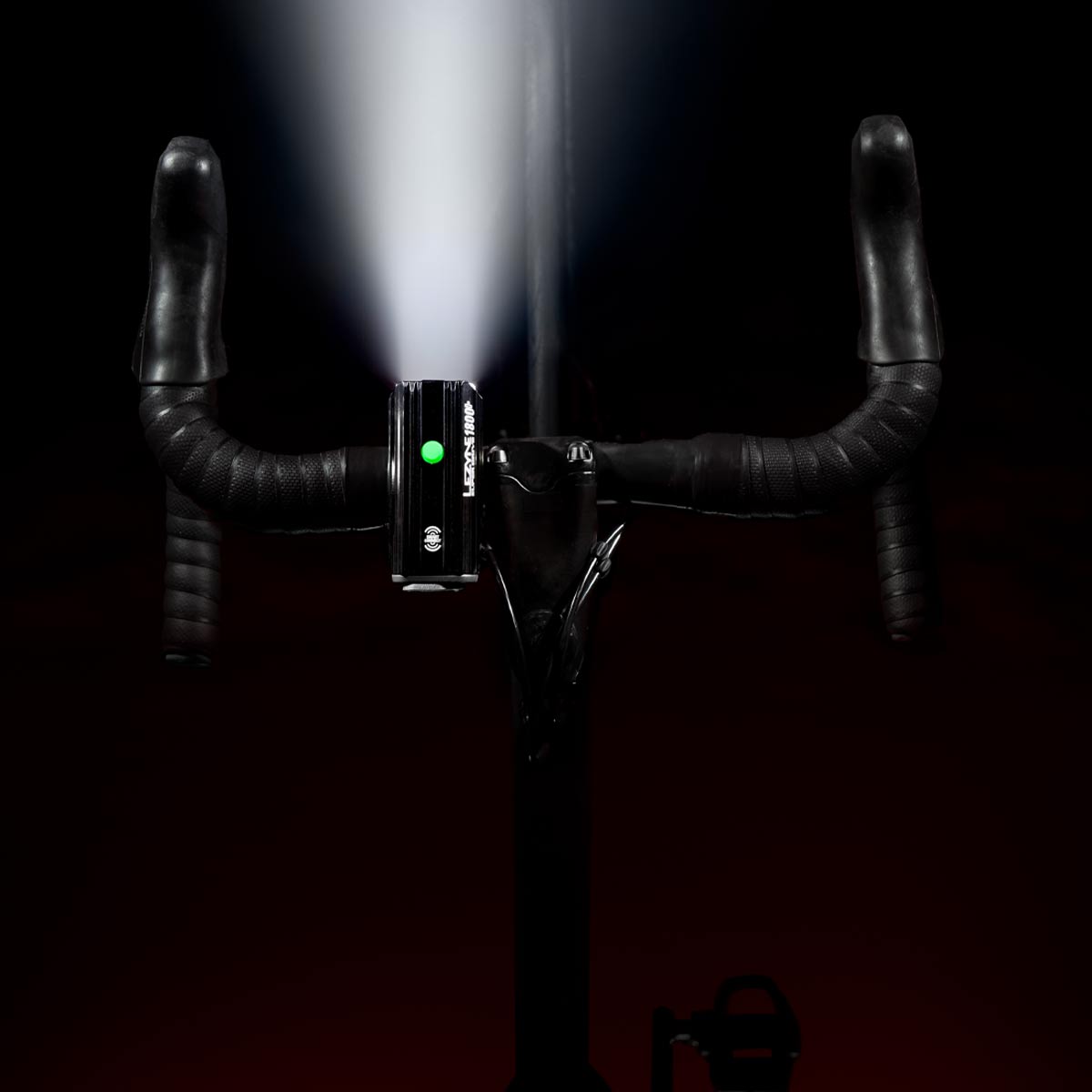 Top view of Super Drive 1800+ mounted on road bike, emitting a bright LED light beam for clear night visibility.