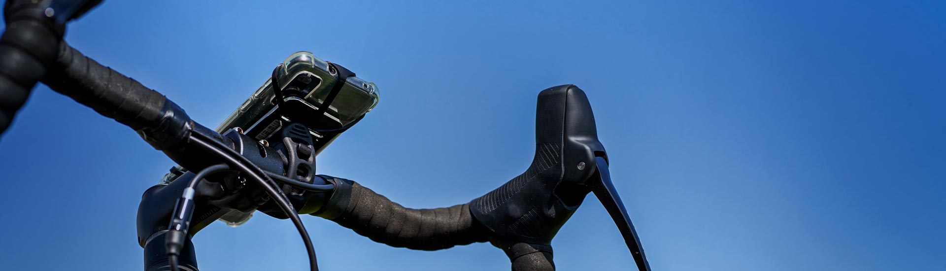 A phone and a light mounted to bicycle handlebars.