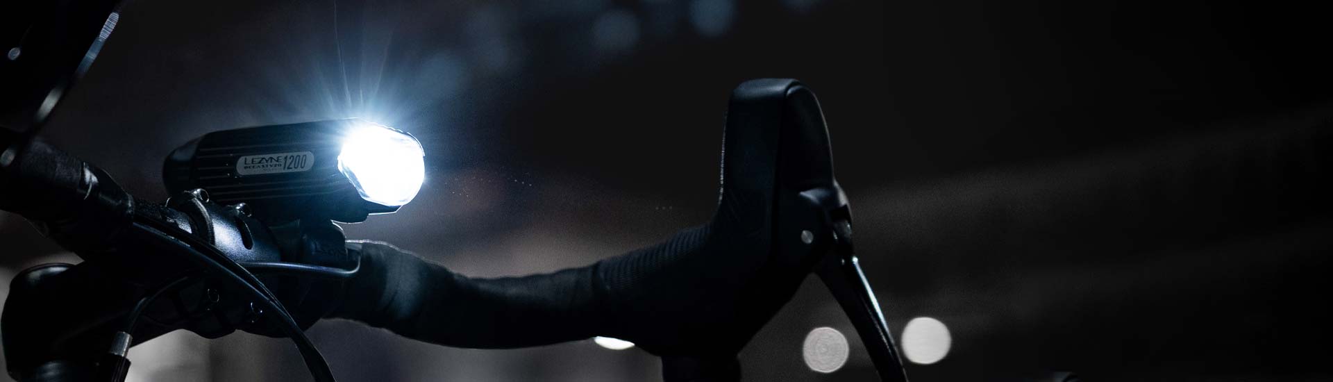 A person wearing gloves holds a bright bike light, emphasizing the strong illumination and secure grip.