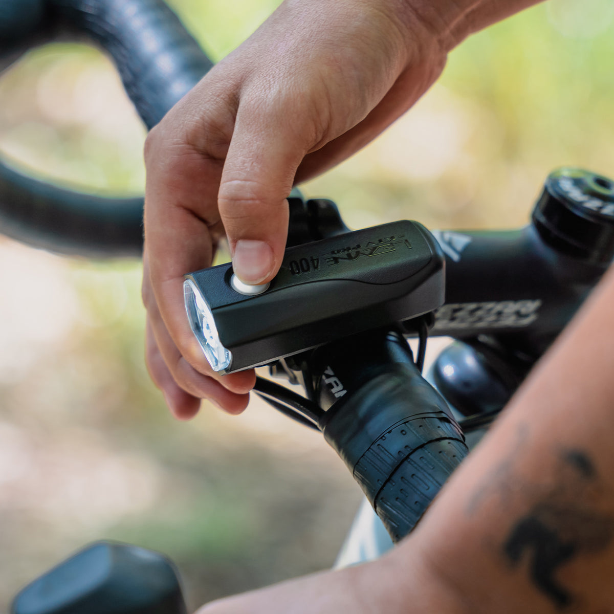 Cyclist pressing the multifunction button on the Lezyne KTV Drive Pro 400+ Front to activate Daytime Flash mode