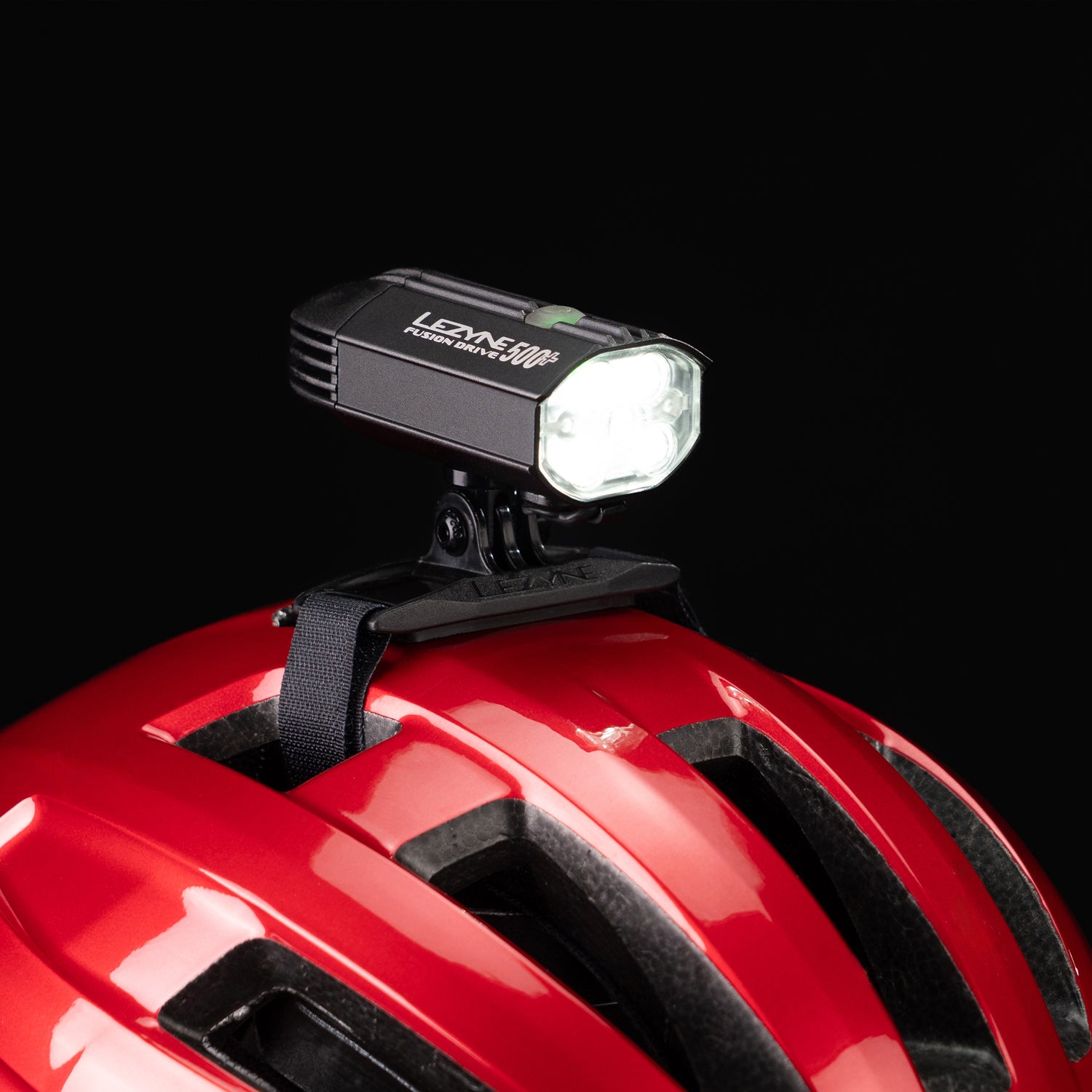 Close-up studio shot of the Lezyne Helmet Fusion Drive 500+ mounted on a red helmet