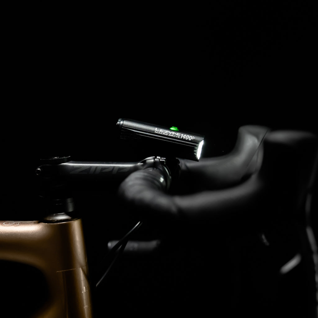 Side view of MACRO DRIVE 1400+ front LED bike light mounted on road bike, perfect for extended night rides.