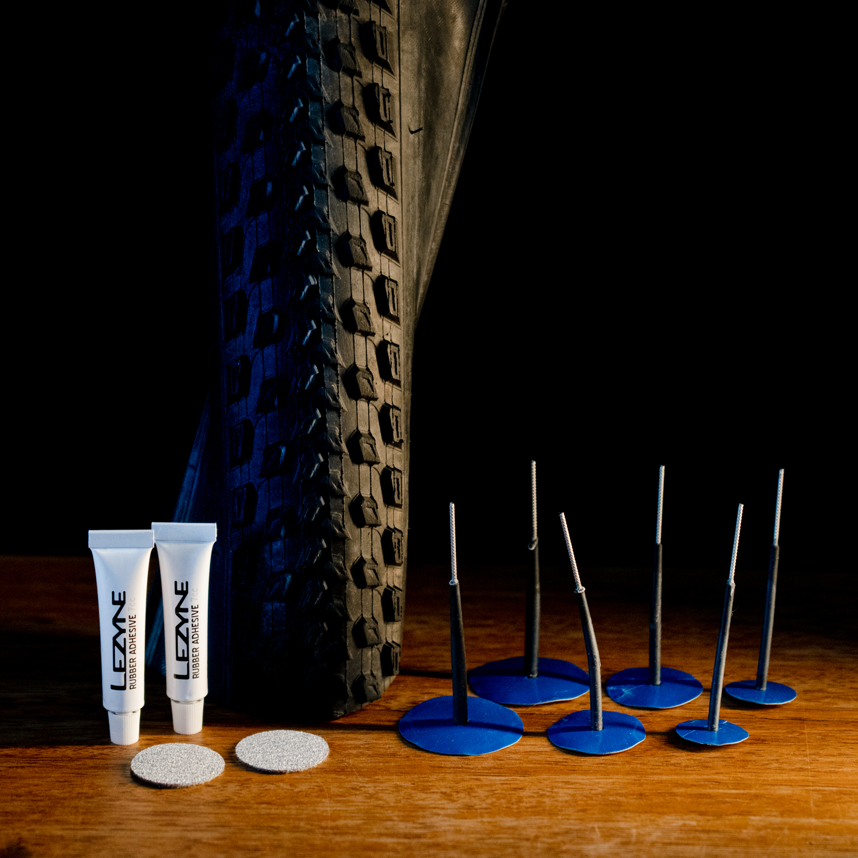 A tubeless tire patch kit in front of a bicycle tire.