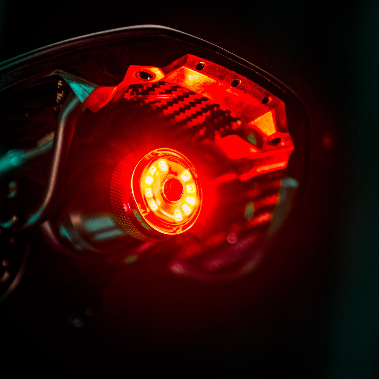 Close-up of SADDLE Ai ALERT 250 REAR LED bike light on road bike saddle, glowing red with a sleek round shape.