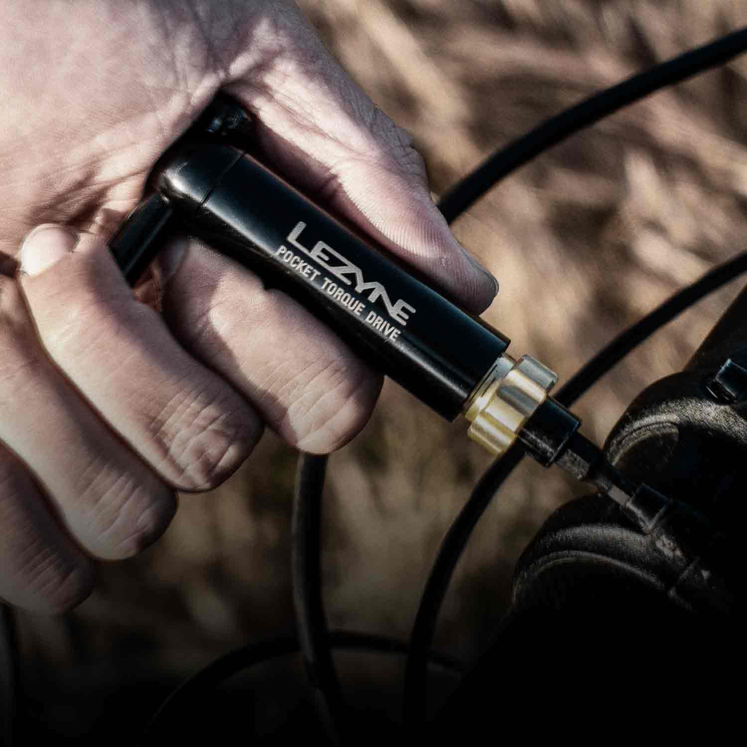 A hand holding a tool with Lezyne Pocket Torque Drive printed on it.