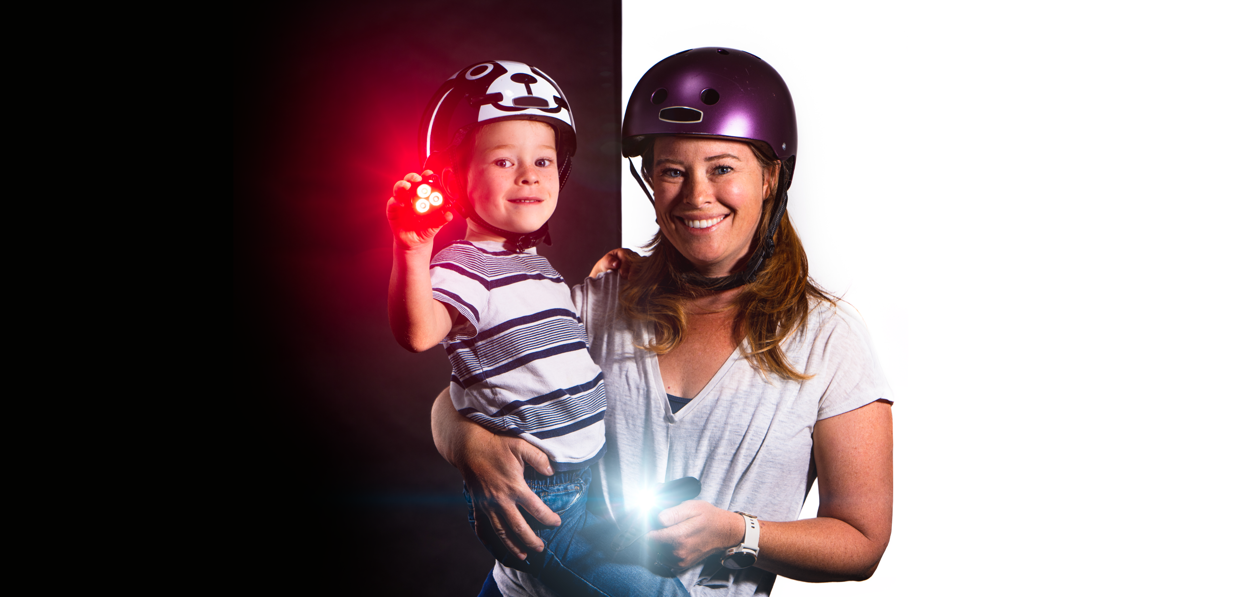 Mother and son wearing helmets while holding a front and rear light