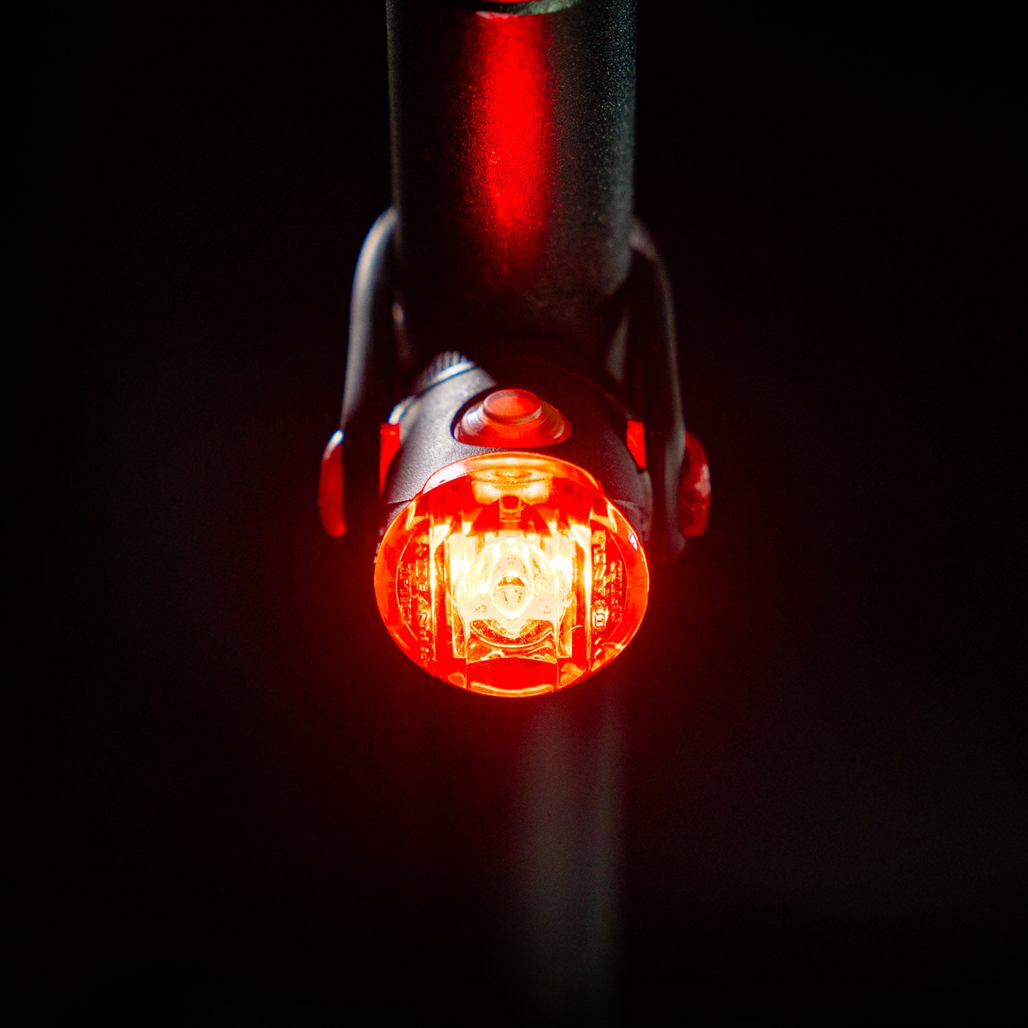 Top-down front view of the circular Lezyne Femto USB Rear StVZO rear bike light, emitting a strong red light, mounted on the seatpost.