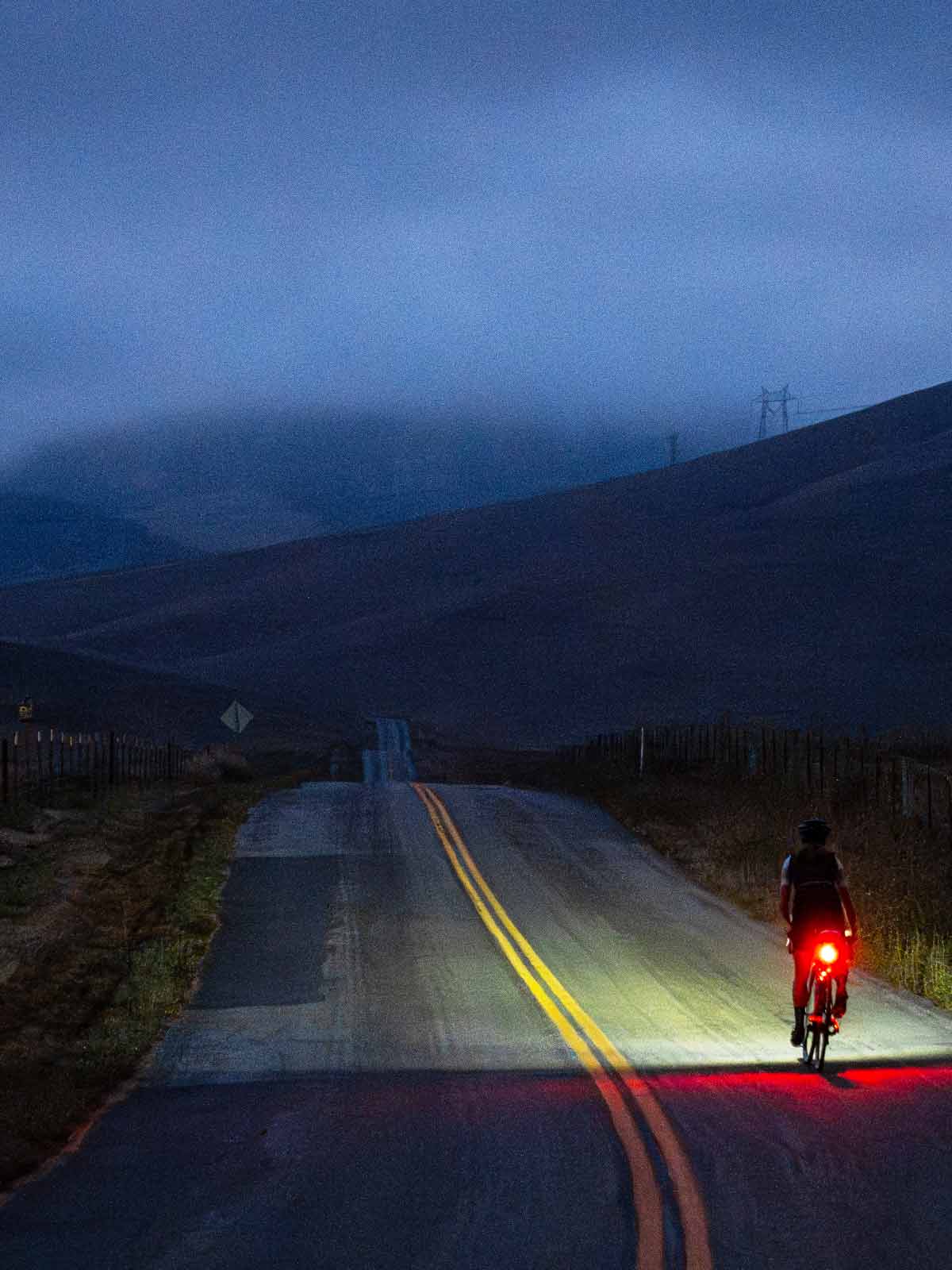 Cyclist on the road in the dark with front leading the way and bright taillight 