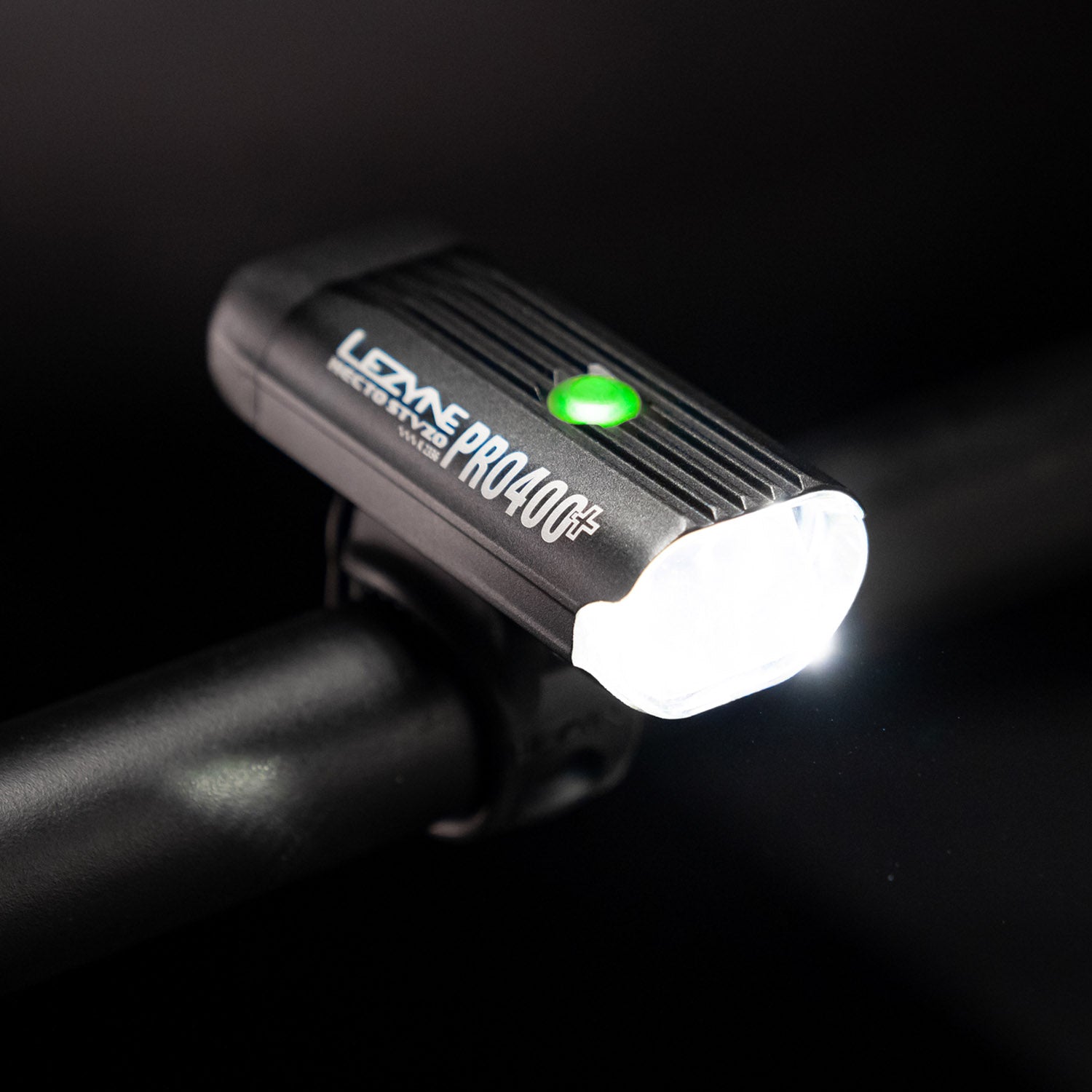 Side view of the Lezyne Hecto Pro StVZO 400+ headlight, a green circular power light on top of the casing, mounted on bike's handlebars.