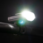 Upward view of the Lezyne Macro StVZO 500+ headlight, angled to the right and emitting a bright white beam, mounted on the handlebars.