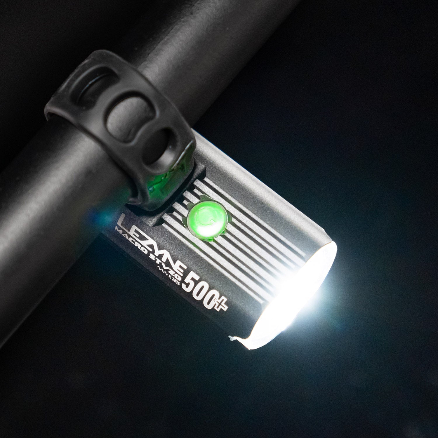 Bird's-eye view of the Lezyne Macro StVZO 500+ Reverse LED light, mounted upside down on the handlebars, angled downwards to the right, with a green circular power light on top.