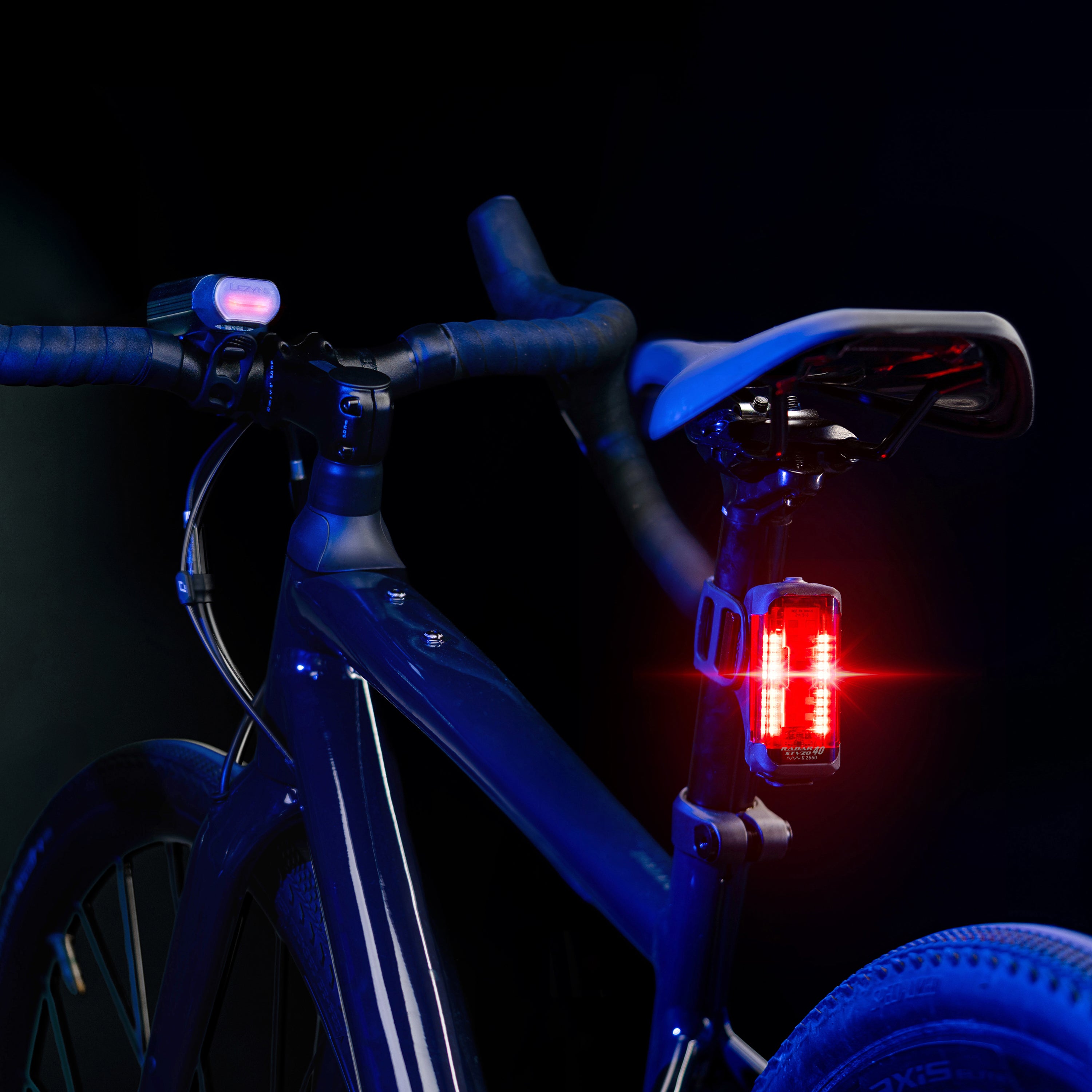 Lezyne Radar React StVZO System on road bike — front light shows active vehicle alert LEDs while rear radar taillight shines brightly.