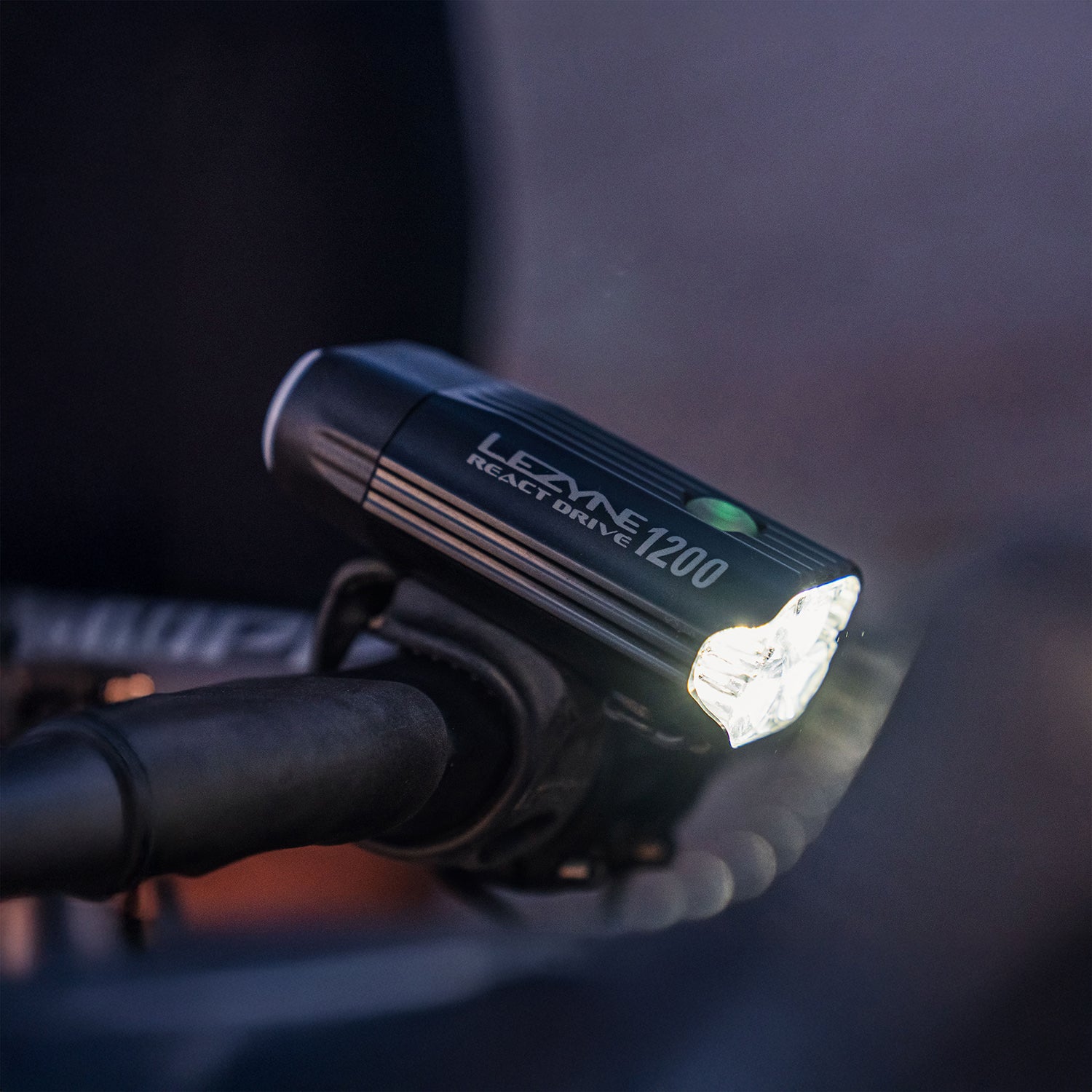 Lezyne React Drive LED front bike light on road bike handlebar at dusk; tidy mount and cable-free look in a lifestyle scene.
