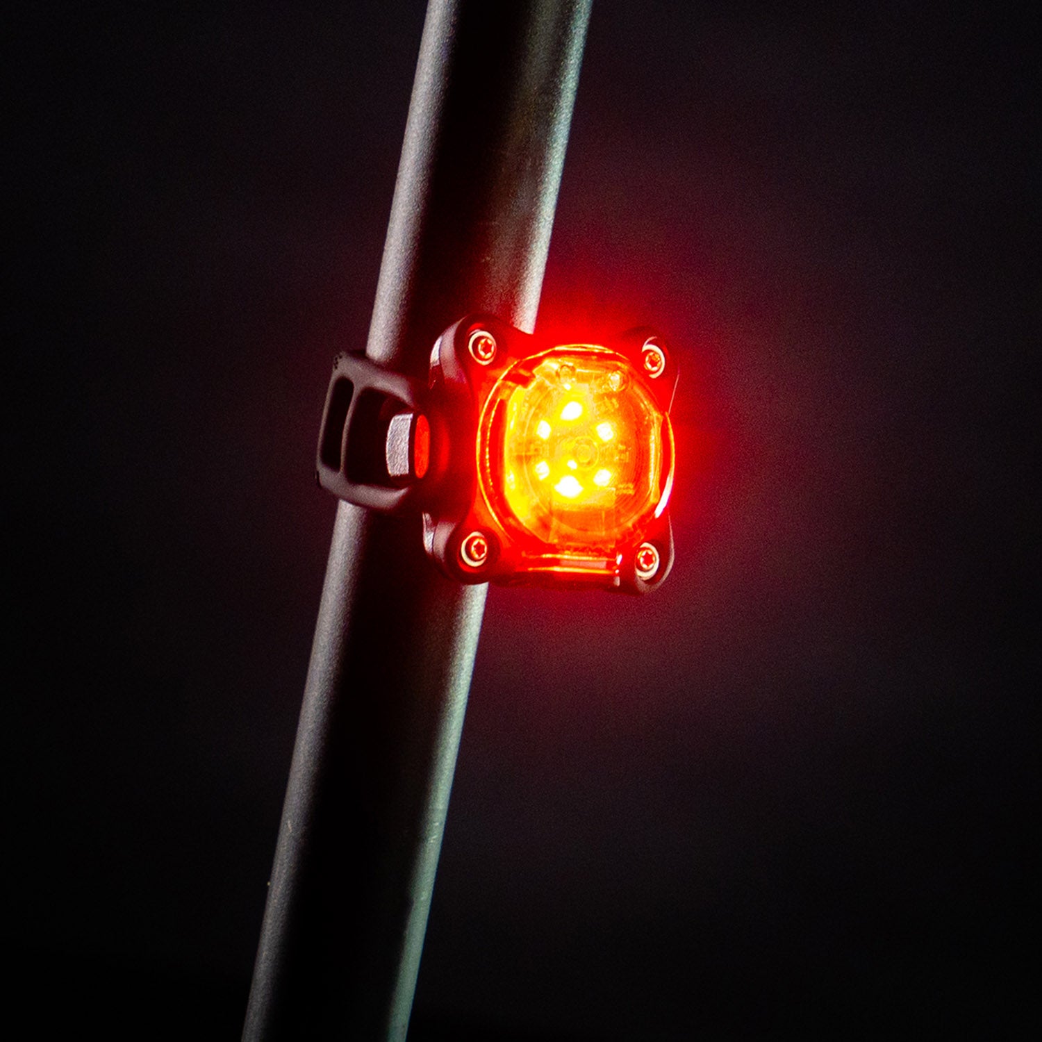 Side view of the small, round Lezyne Zecto StVZO Rear LED light, emitting a bright red light, mounted on the seat post.