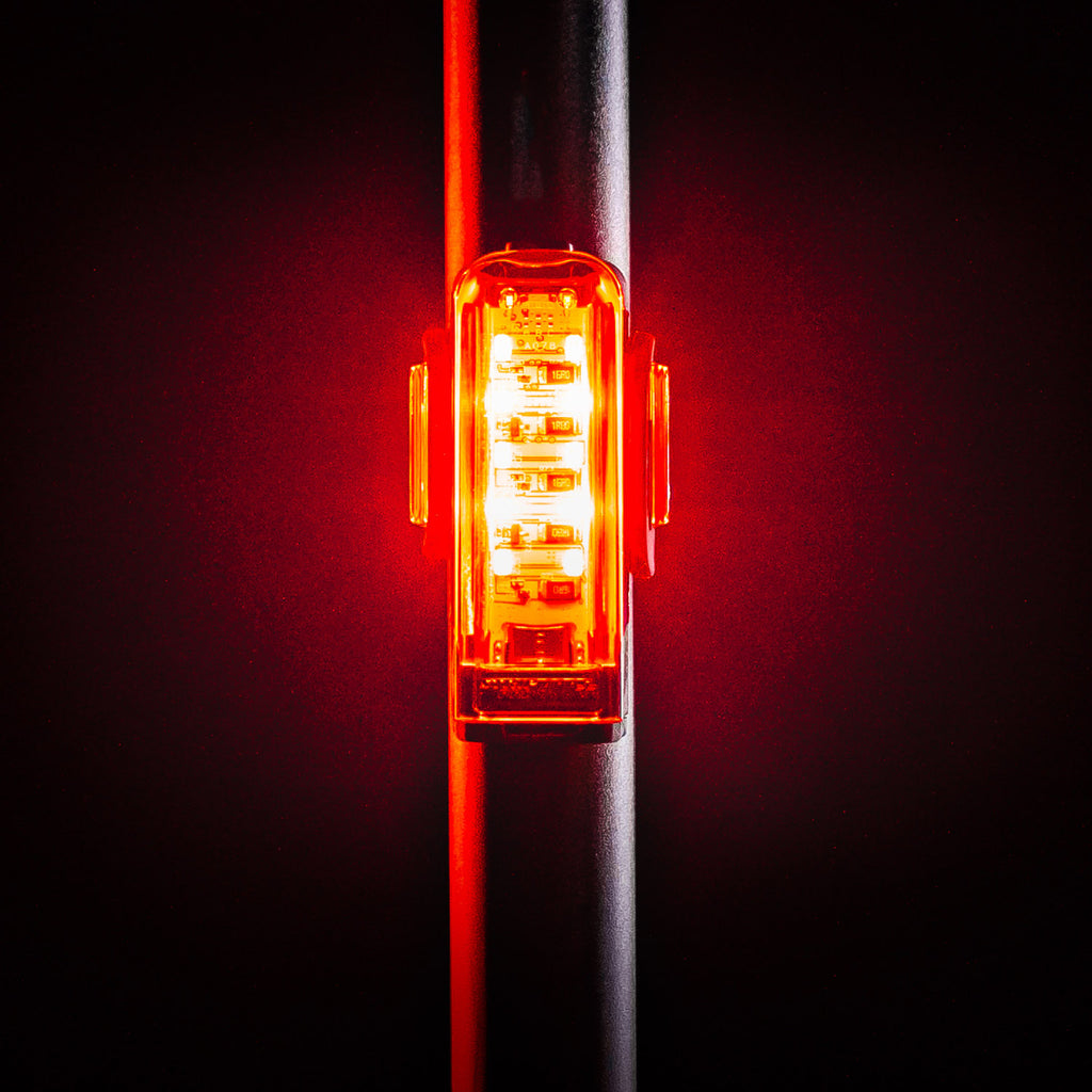 Front view of Lezyne Strip Pro Ai Alert 400+ smart LED rear bike light, emitting bright red light, saddle bar mounted for high visibility on the street.