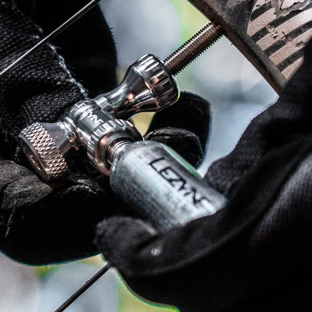 Mountain biker using silver Control Drive CO2 inflator on the trail, shown with threaded cartridge and twist valve control.